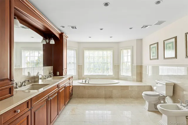 a spacious bathroom with a double vanity sink a large mirror and a bathtub