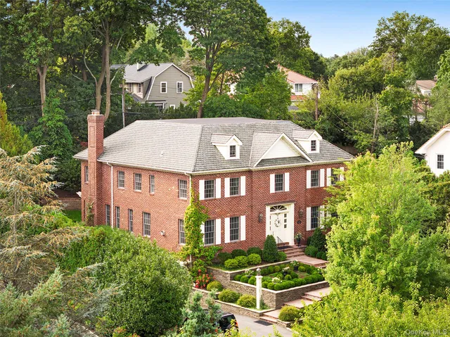 a aerial view of a brick house next to a yard with plants and trees