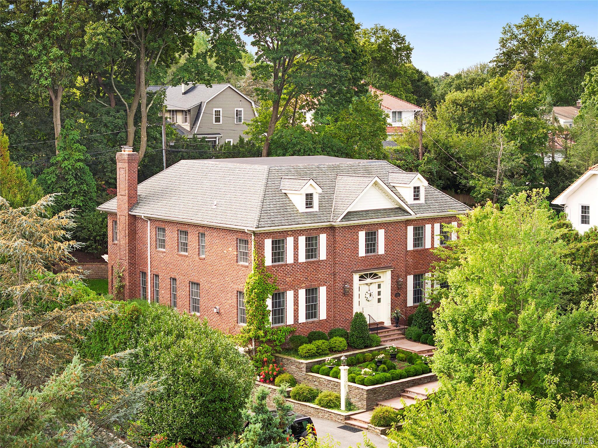 1270 Plandome Road Manhasset, NY 11030 - Photo 21 of 23 a aerial view of a brick house next to a yard with plants and trees