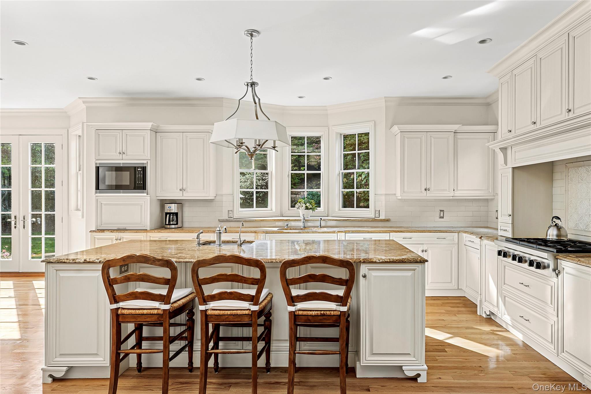 1270 Plandome Road Manhasset, NY 11030 - Photo 8 of 23 a kitchen with granite countertop white cabinets and chairs