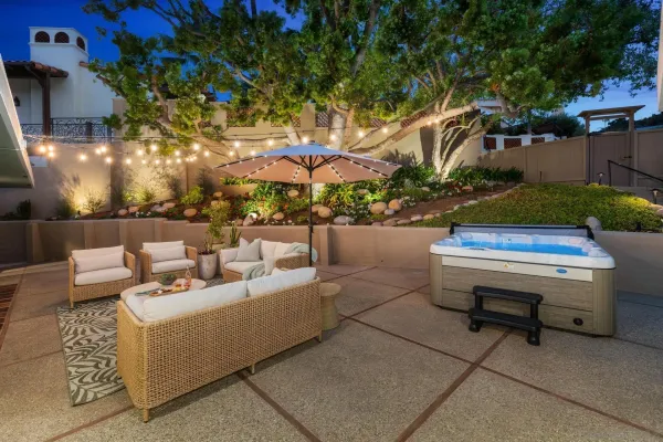 a view of a patio with couches and a fire pit and wooden fence