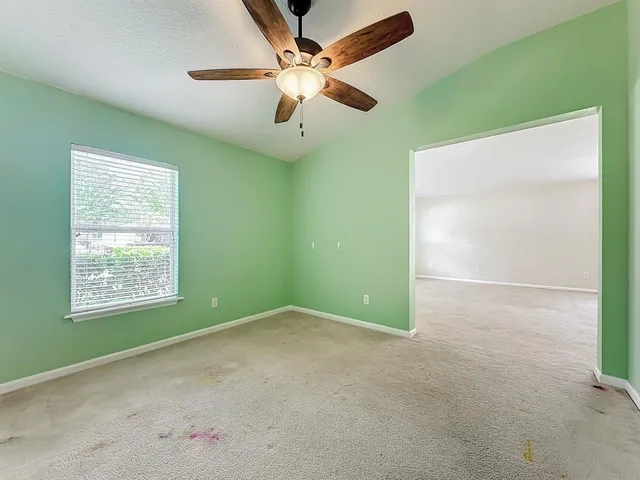 an empty room with windows and chandelier fan