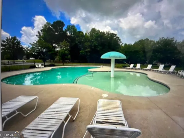 a swimming pool with lawn chairs and plants