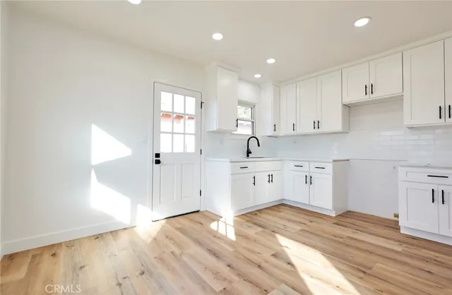a kitchen with granite countertop a sink cabinets and wooden floor