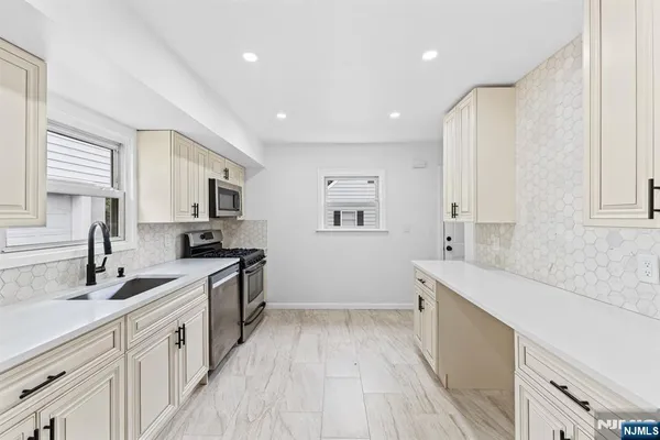 a large white kitchen with a large window a sink and white appliances