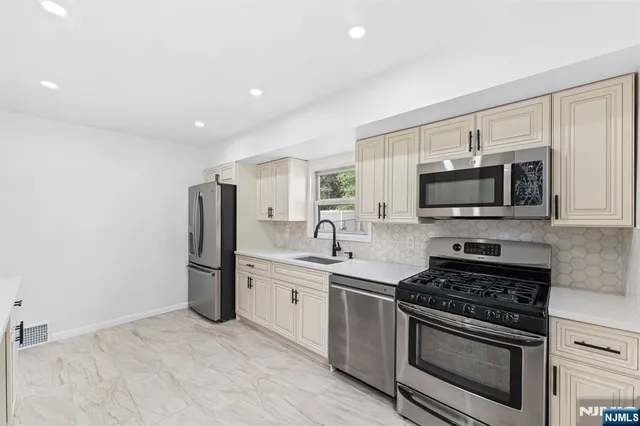 a kitchen with stainless steel appliances a stove a microwave and a sink