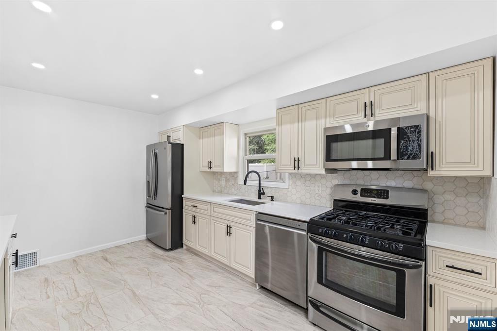 18 Farmingdale Avenue Bloomfield, NJ 07003 - Photo 14 of 50 a kitchen with stainless steel appliances a stove a microwave and a sink