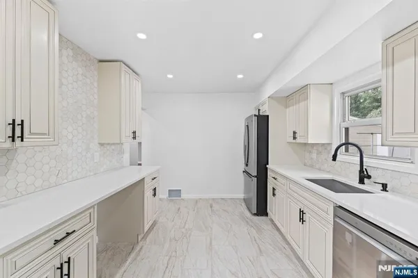 a large white kitchen with a sink stainless steel appliances and cabinets