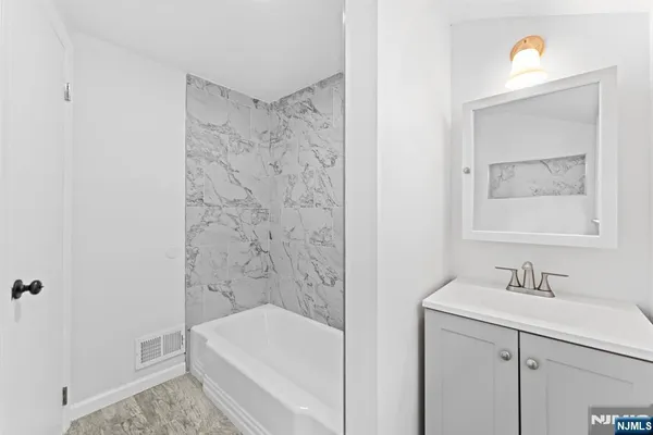 a bathroom with a bathtub a sink a vanity and a shower