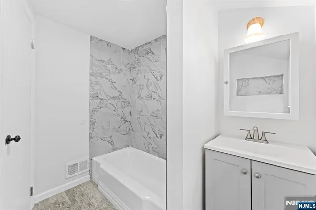 a bathroom with a bathtub a sink a vanity and a shower