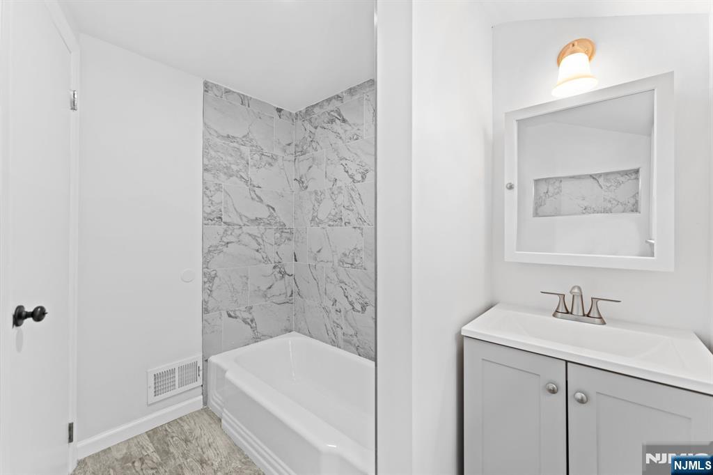 18 Farmingdale Avenue Bloomfield, NJ 07003 - Photo 23 of 50 a bathroom with a bathtub a sink a vanity and a shower