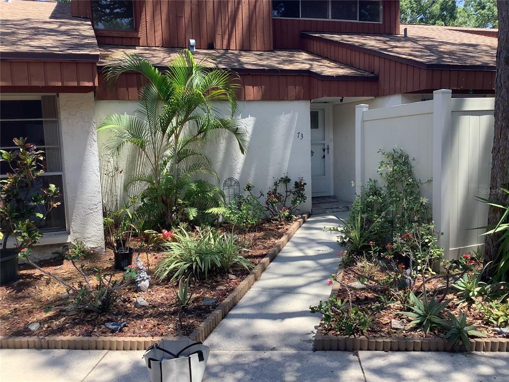 2064 Sunset Point Road, Unit 73 Clearwater, FL 33765 - Photo 44 of 58 a view of a house with plants and a bench