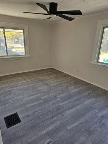 an empty room with wooden floor closet and windows