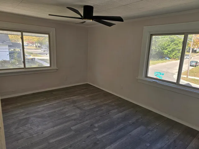 an empty room with wooden floor and windows