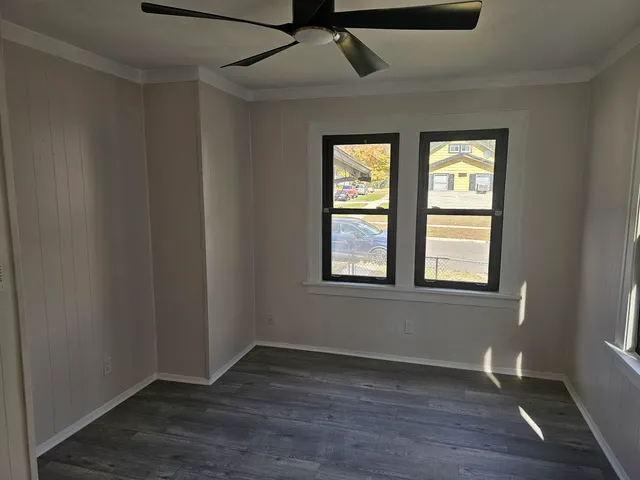 a view of an empty room with wooden floor and a window