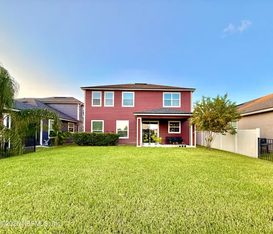 a view of a house next to a big yard and large trees