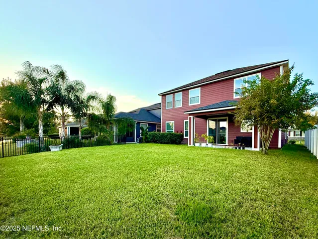 a view of a brick house with a yard potted plants and a table