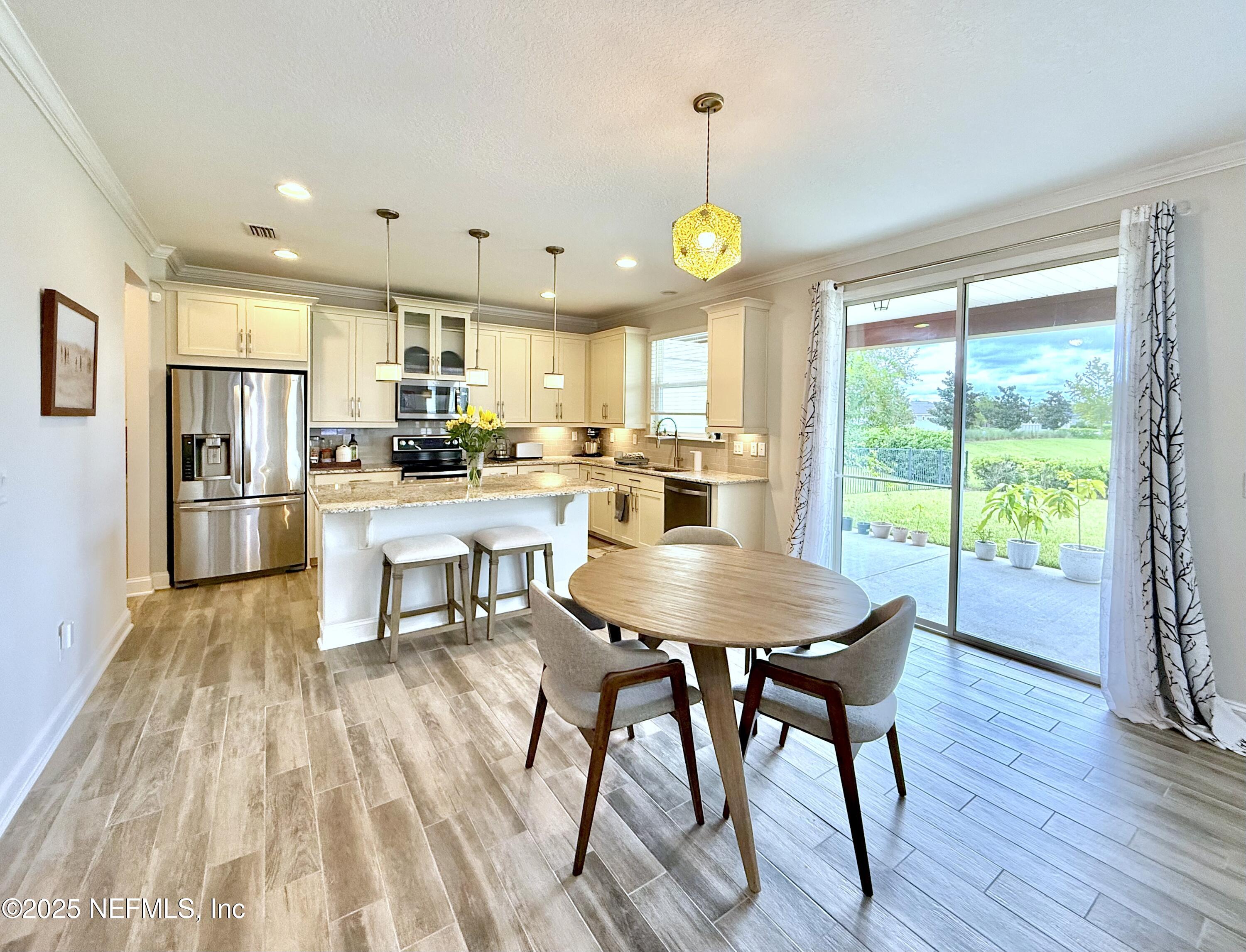 6887 Azalea Grove Drive Jacksonville, FL 32258 - Photo 9 of 35 a kitchen with a table chairs refrigerator and microwave