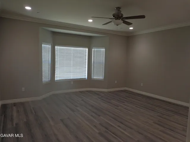 an empty room with wooden floor chandelier fan and windows