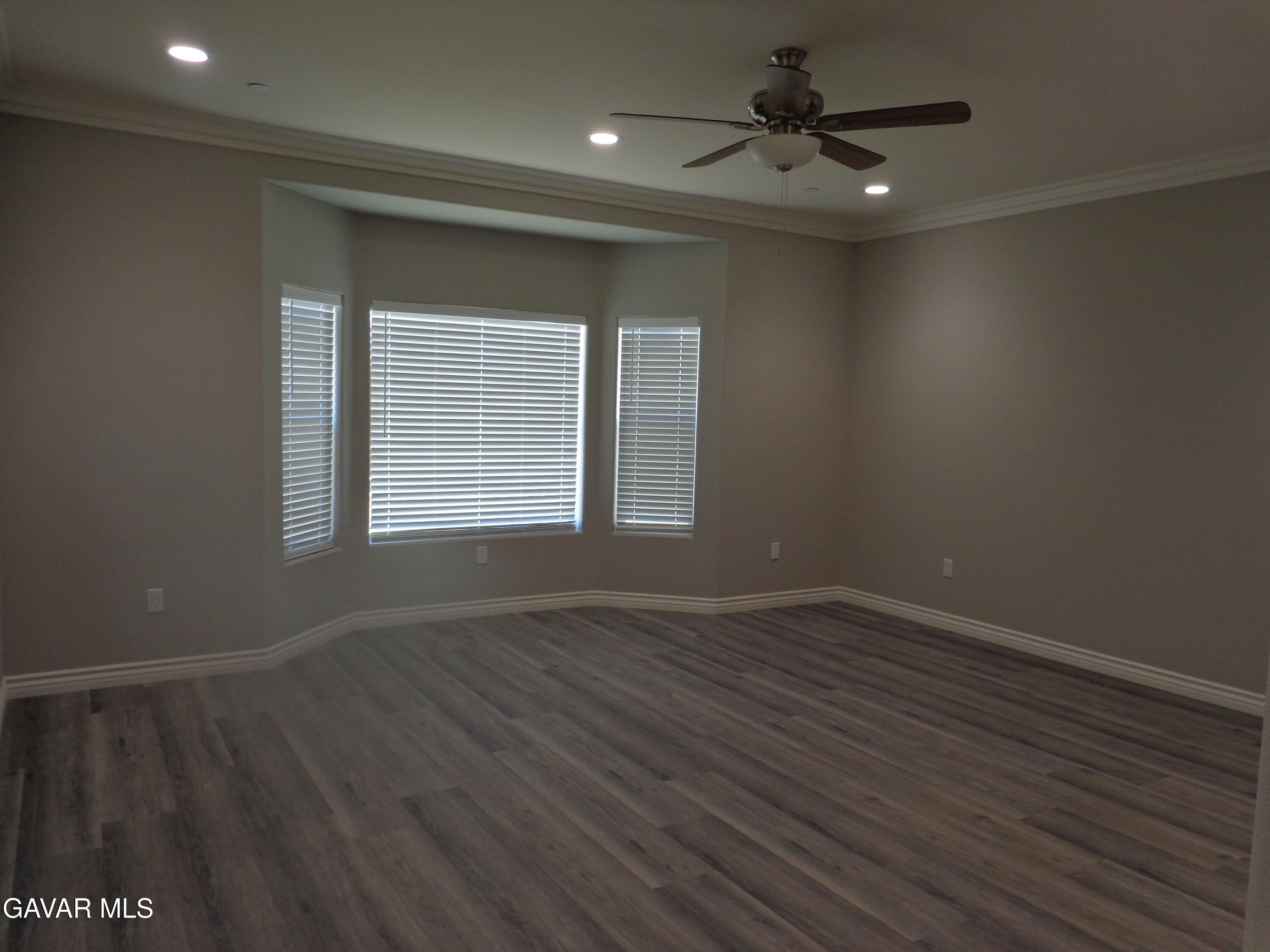 18255 Winnetka Road Apple Valley, CA 92307 - Photo 12 of 33 an empty room with wooden floor chandelier fan and windows