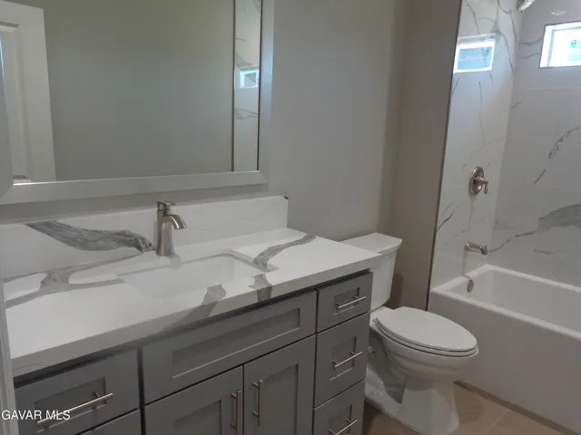 a bathroom with a granite countertop toilet sink and mirror