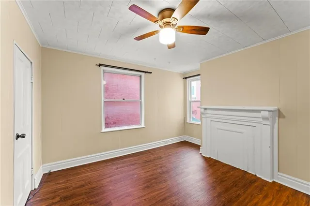 an empty room with wooden floor chandelier fan and windows
