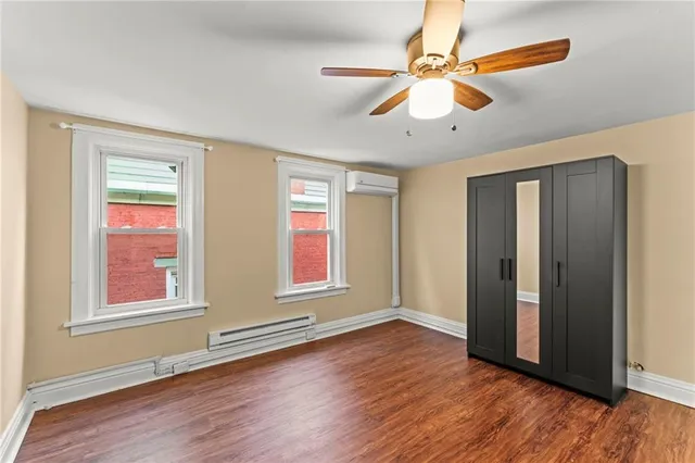 a view of an empty room with window and wooden floor