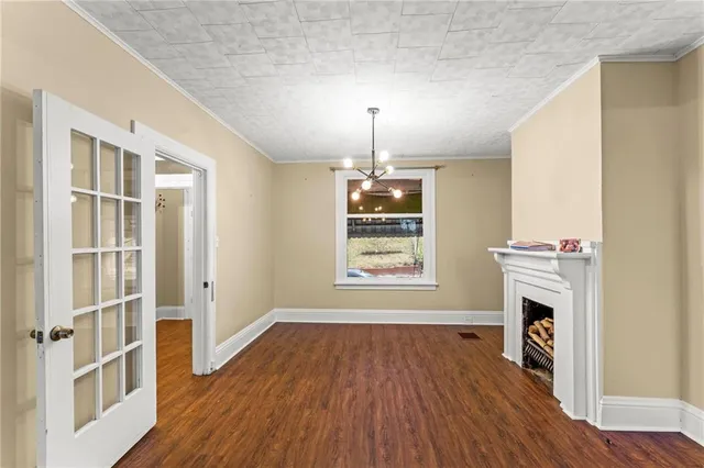 an empty room with wooden floor fireplace and windows