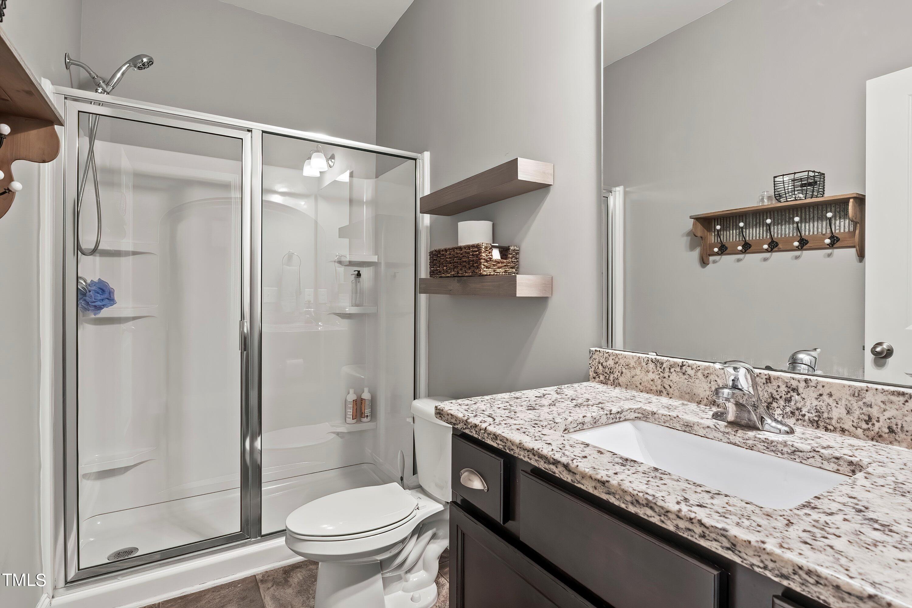 7406 Randshire Way Raleigh, NC 27616 - Photo 18 of 38 a bathroom with a granite countertop sink toilet and shower glass cabinet