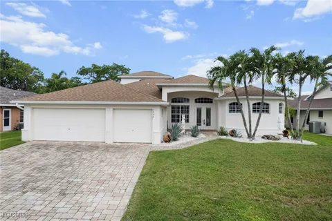 a front view of a house with a yard and palm trees