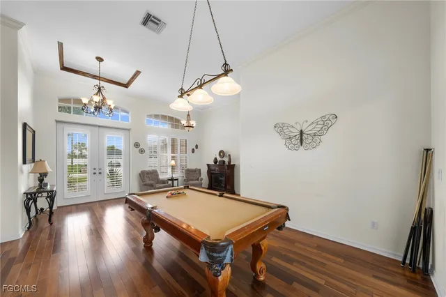 a dining room with wooden floor a chandelier a wooden table and chairs