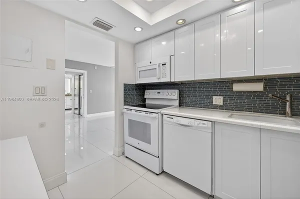 a kitchen with white cabinets and white appliances