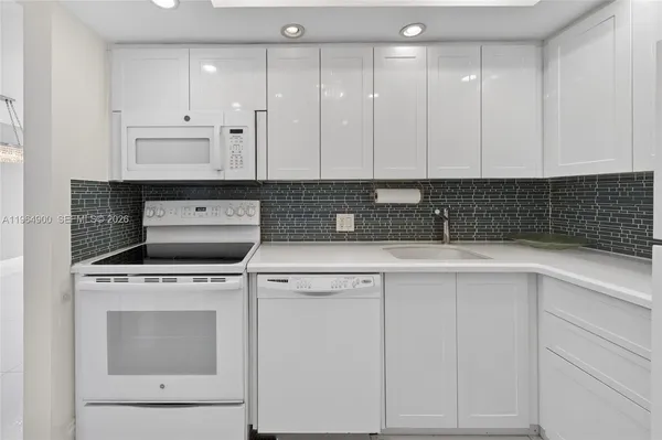 a kitchen with granite countertop white cabinets and white appliances