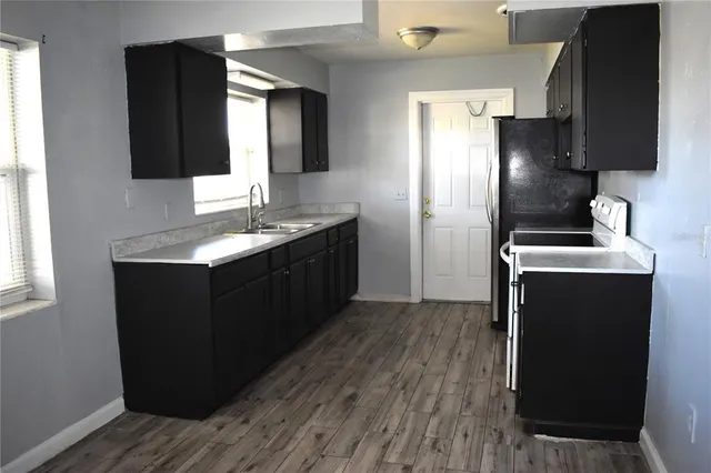 a kitchen with stainless steel appliances granite countertop a refrigerator a sink and wooden floor