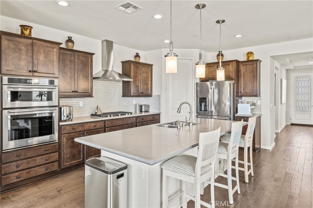 11636 Cascade Street Apple Valley, CA 92308 - Photo 16 of 70 a kitchen with stainless steel appliances granite countertop a refrigerator a stove top oven a sink dishwasher and white cabinets with wooden floor