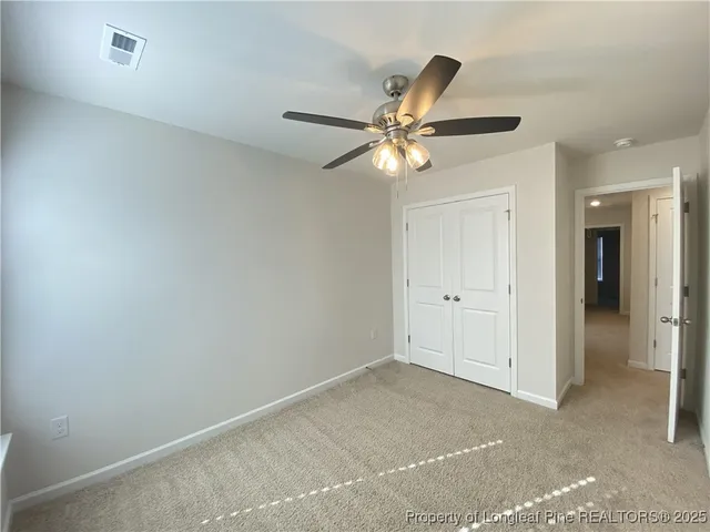 an empty room with closet and a ceiling fan