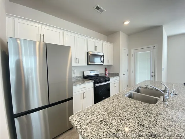 a kitchen with granite countertop a refrigerator stove and sink