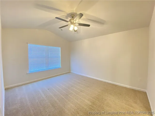 a view of an empty room with wooden floor and a ceiling fan