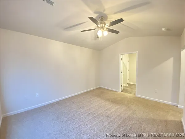 an empty room with a chandelier fan and windows