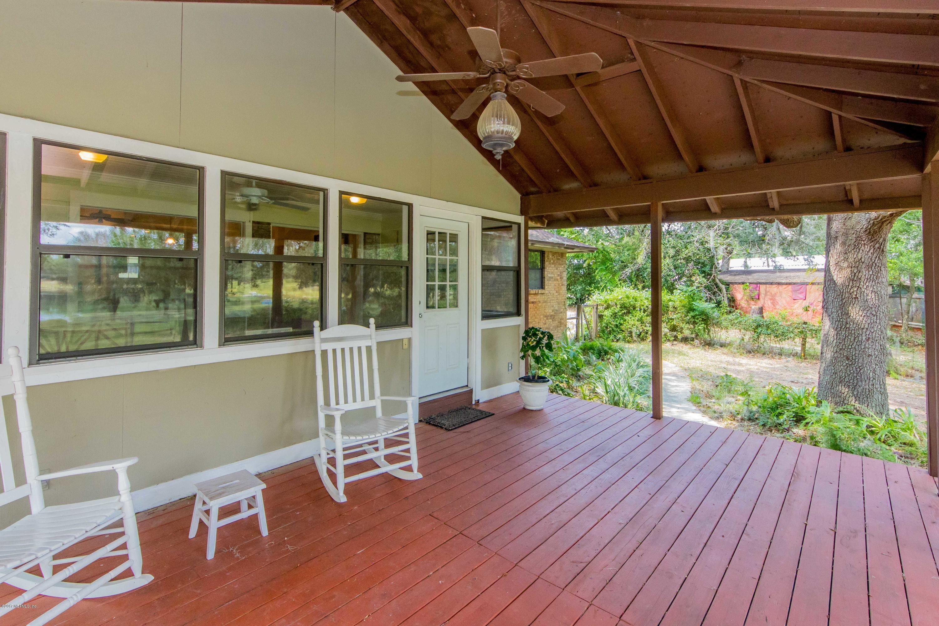 6255 Little Lake Geneva Road Keystone Heights, FL 32656 - Photo 36 of 59 a porch area with wooden floor outdoor seating and yard