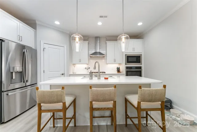 a kitchen with stainless steel appliances granite countertop a sink a stove a refrigerator cabinets a dining table and chairs