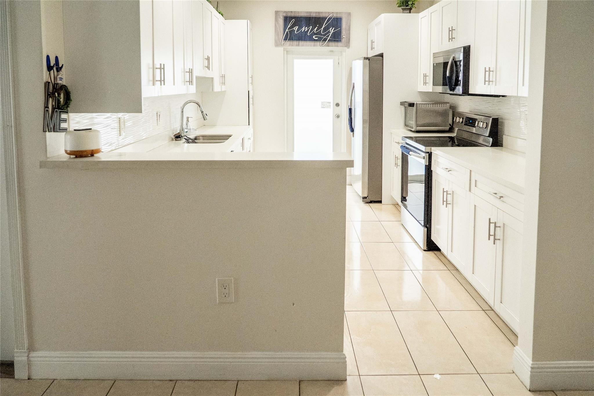 2710 Northwest 5th Street Pompano Beach, FL 33069 - Photo 7 of 31 a kitchen with stainless steel appliances a sink and a refrigerator