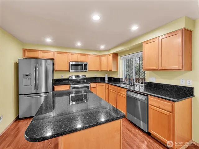 a kitchen with stainless steel appliances granite countertop a sink refrigerator and microwave