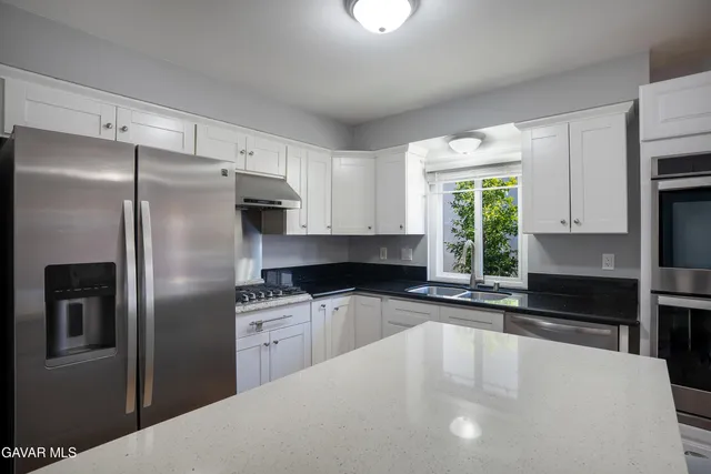 a kitchen with stainless steel appliances a refrigerator sink and white cabinets