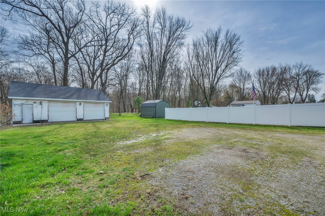 View of yard featuring an outdoor structure, fence, and a garage