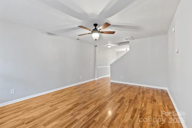 an empty room with wooden floor a ceiling fan and fan