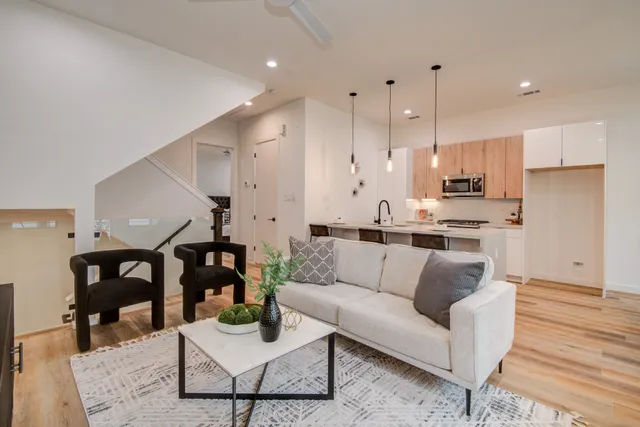 a living room with stainless steel appliances kitchen island a sink and wooden floor