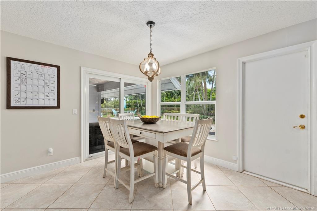 18770 Southeast River Ridge Road Jupiter, FL 33469 - Photo 11 of 81 a dining room with furniture large windows and a chandelier