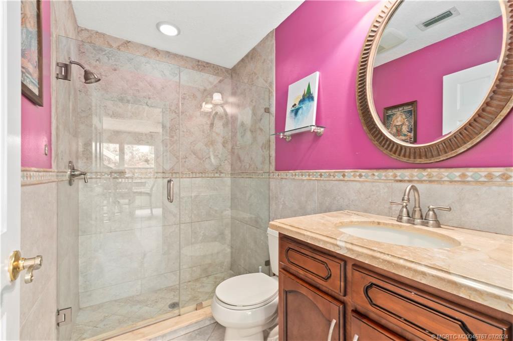 18770 Southeast River Ridge Road Jupiter, FL 33469 - Photo 50 of 81 a bathroom with a sink a mirror a toilet and a shower