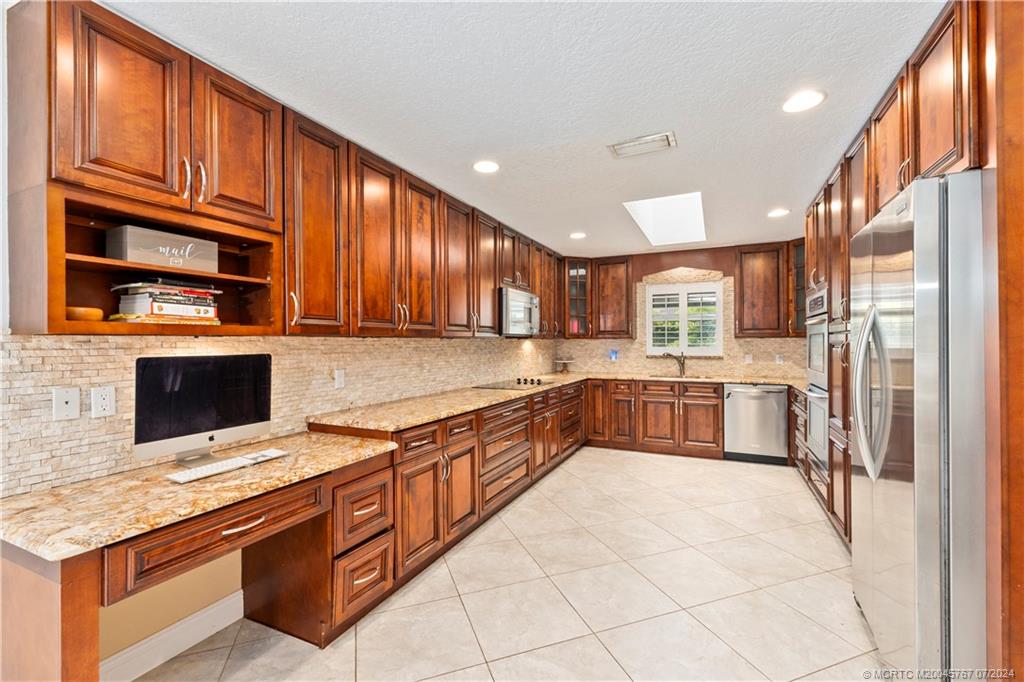 18770 Southeast River Ridge Road Jupiter, FL 33469 - Photo 5 of 81 a kitchen with stainless steel appliances granite countertop a stove a sink and a microwave
